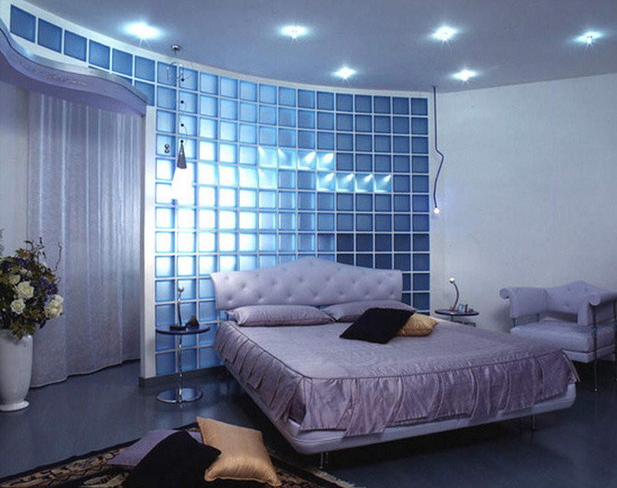 Широкая кровать в спальне с перегородкой из стеклянных блоков