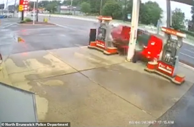 After losing control, the red car flips onto its side and slams into the two fuel pumps at the station